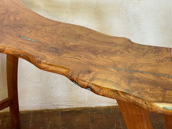 Rustic wooden bench with a live-edge seat against a plain wall.