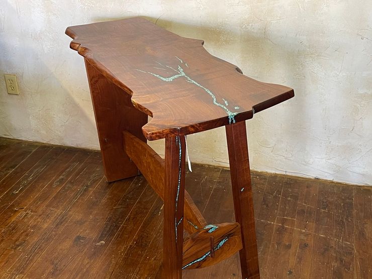 Small wooden table with a cracked top and blue tape in a sparse room