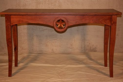 Wooden console table with a star-carved center panel and curved legs on a plain backdrop
