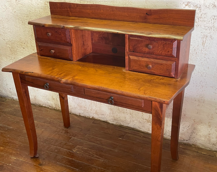 Wooden antique secretary desk with drawers and cubbies on a hardwood floor
