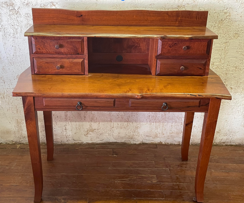 Wooden secretary desk with drawers and fold-down writing surface on a wood floor.