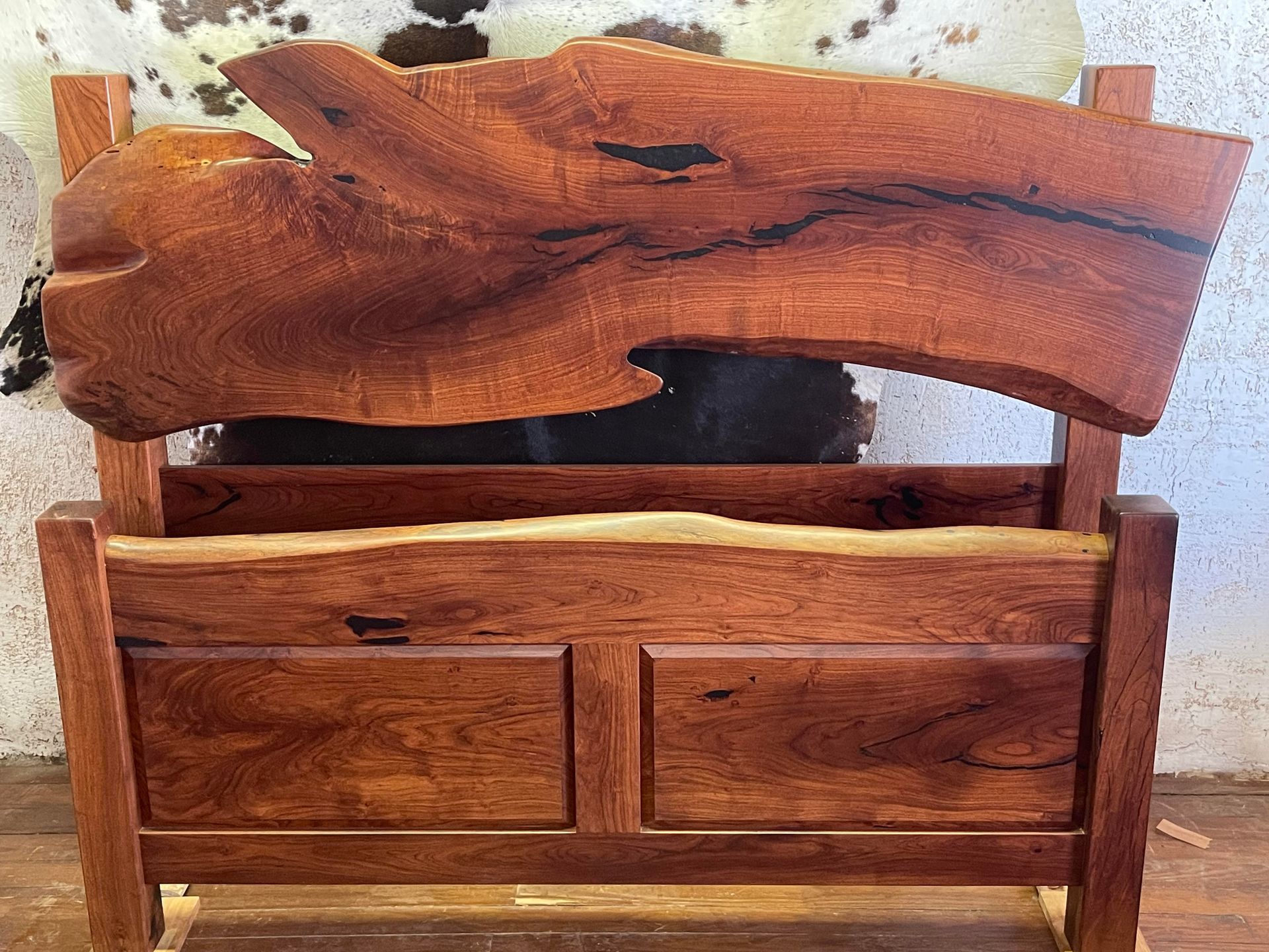 Wooden side table with a live-edge top and two front drawers against a tiled wall.