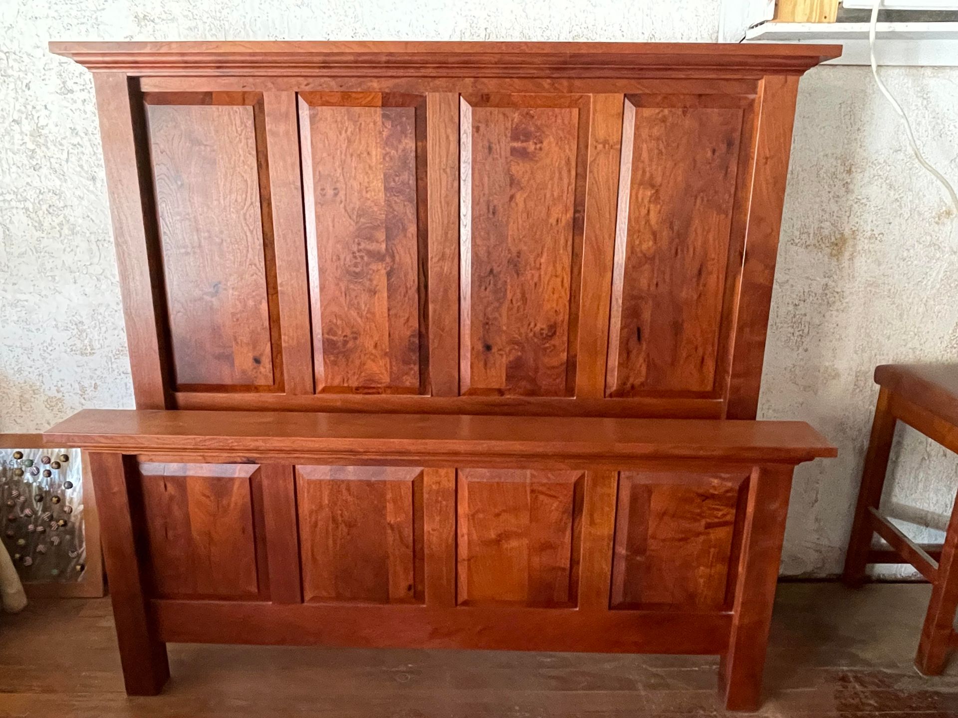 Wooden bench with tall backrest and vertical panels against a light wall.