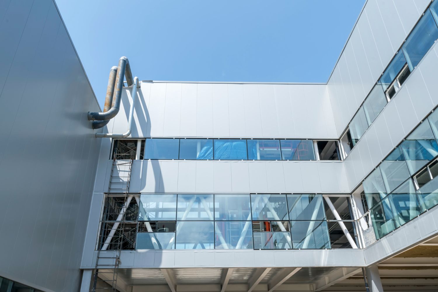 Modern building exterior with glass windows and metal walkways under a clear blue sky