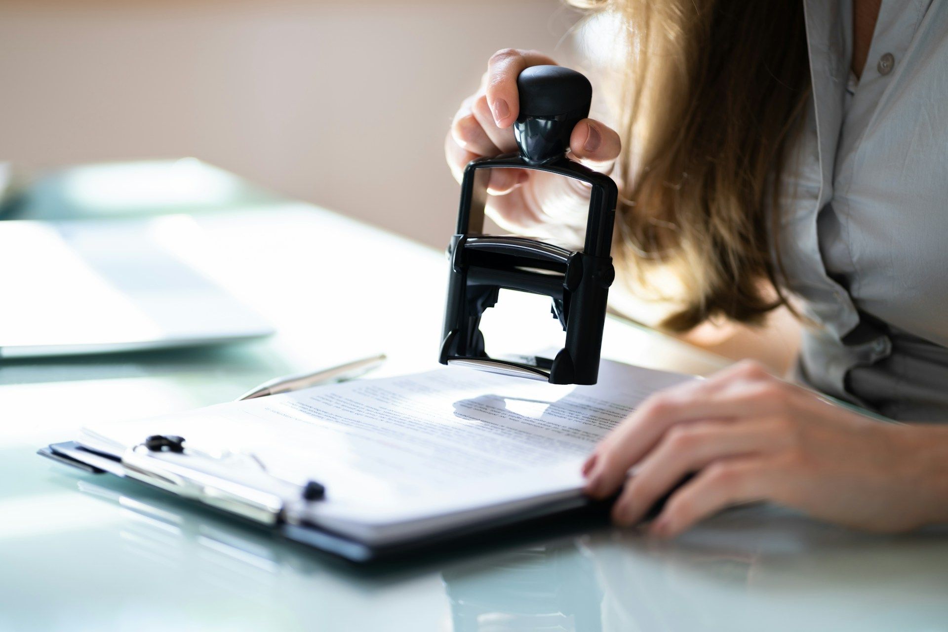 Hand stamping a document on a clipboard at a desk