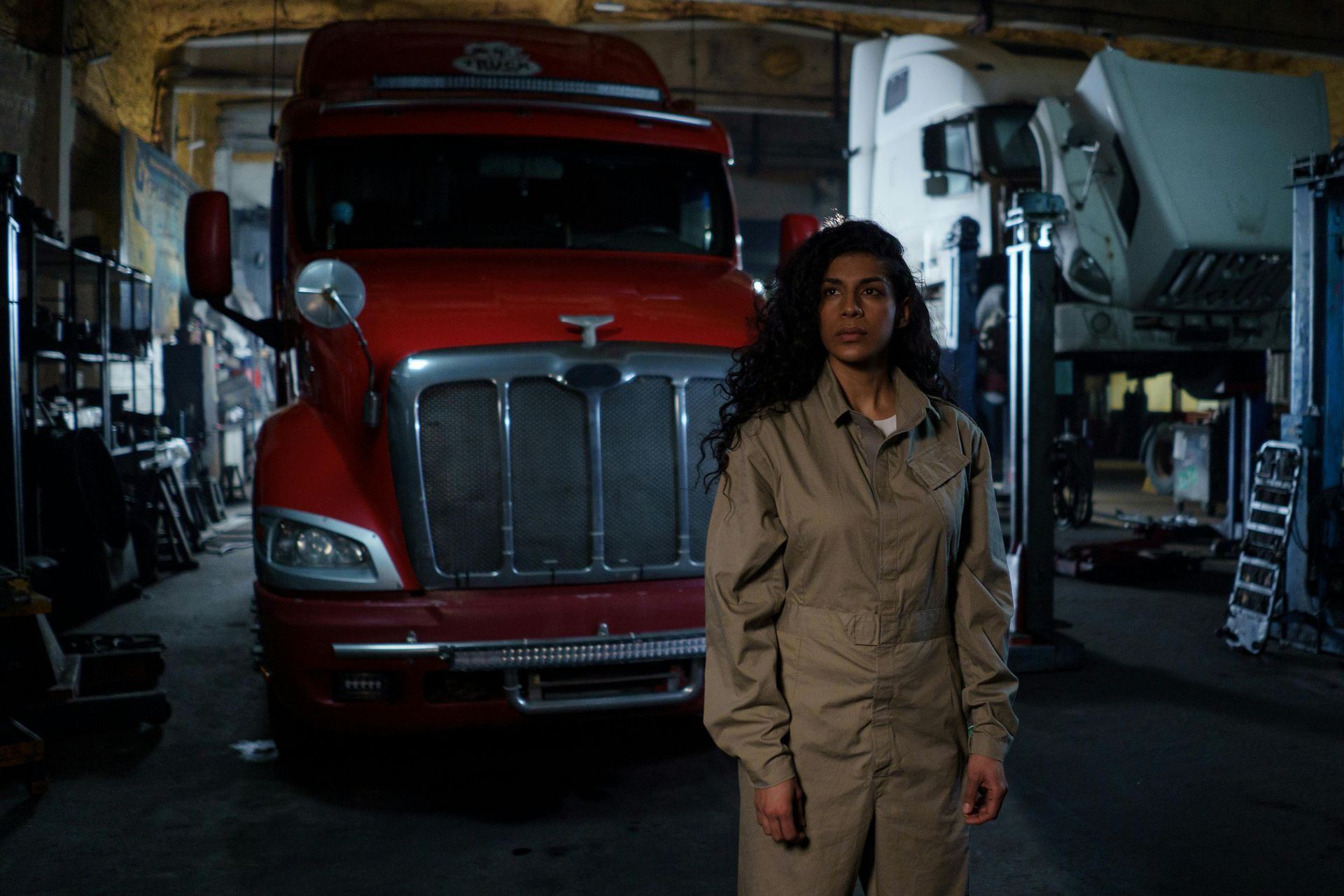 Person standing in a dim garage in front of a red semi truck