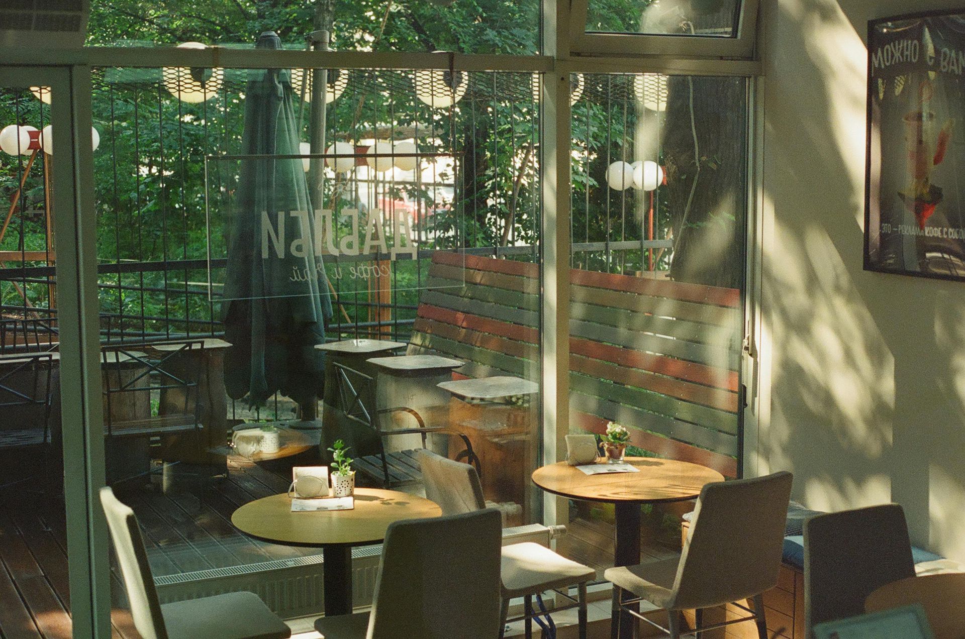 Sunlit café interior with empty tables and chairs by large windows and glass doors