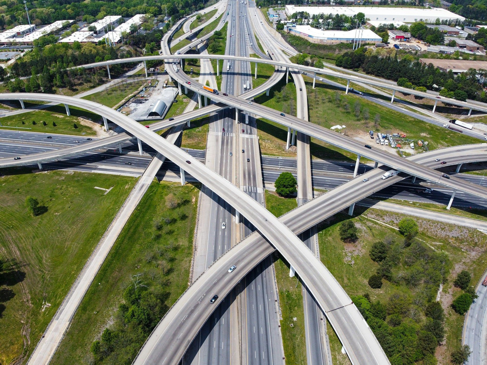 Aerial view of a multi-level highway interchange with crossing overpasses and surrounding green grass.