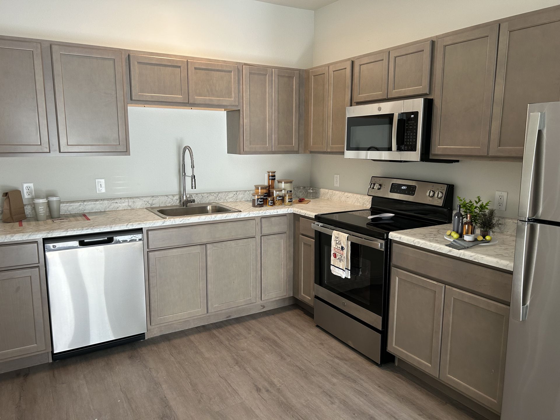 Lincoln, NE, Affordable Apartments for Rent - Union at Middle Creek - Kitchen With Gray Cabinets, Marble Look Countertops, Stainless Steel Appliances, And Wood Style Flooring.