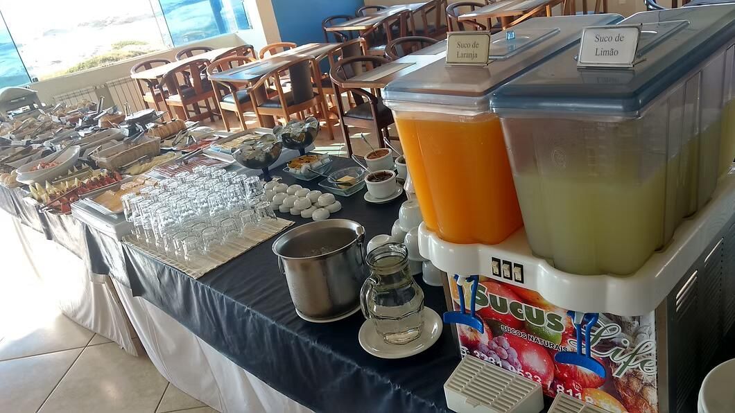 Mesa de bufê com bandejas, travessas com tampa e dispensadores de bebidas em um refeitório