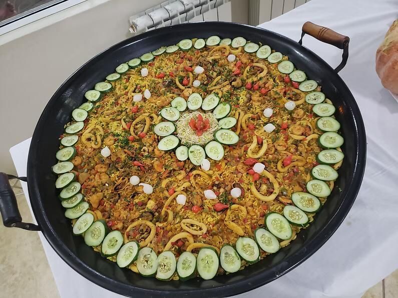 Grande prato redondo de arroz amarelo coberto com fatias de pepino, rabanete e limão dispostas em um padrão decorativo