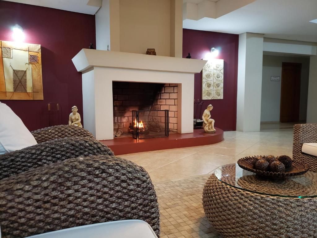 Sala de estar aconchegante com uma lareira acesa, cadeiras de vime e paredes de destaque em bordô.