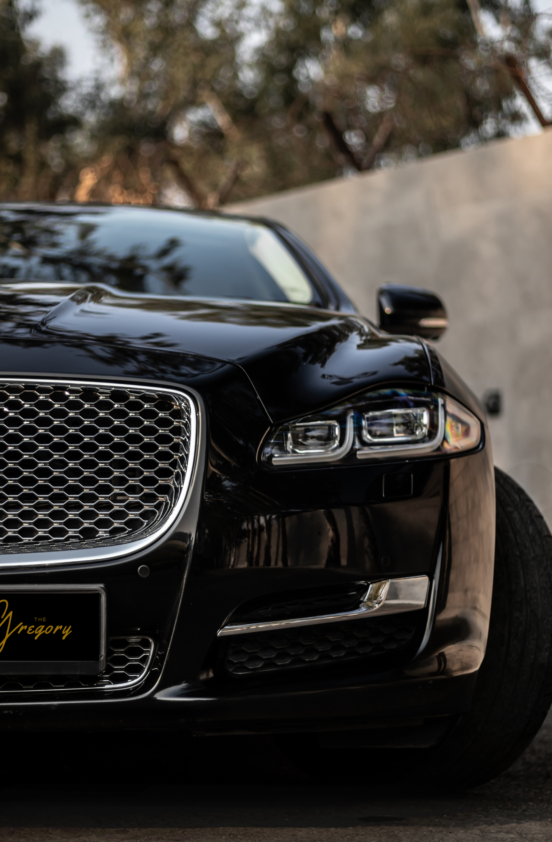 Front view of a black luxury car with a chrome grille and sleek headlights on a road.