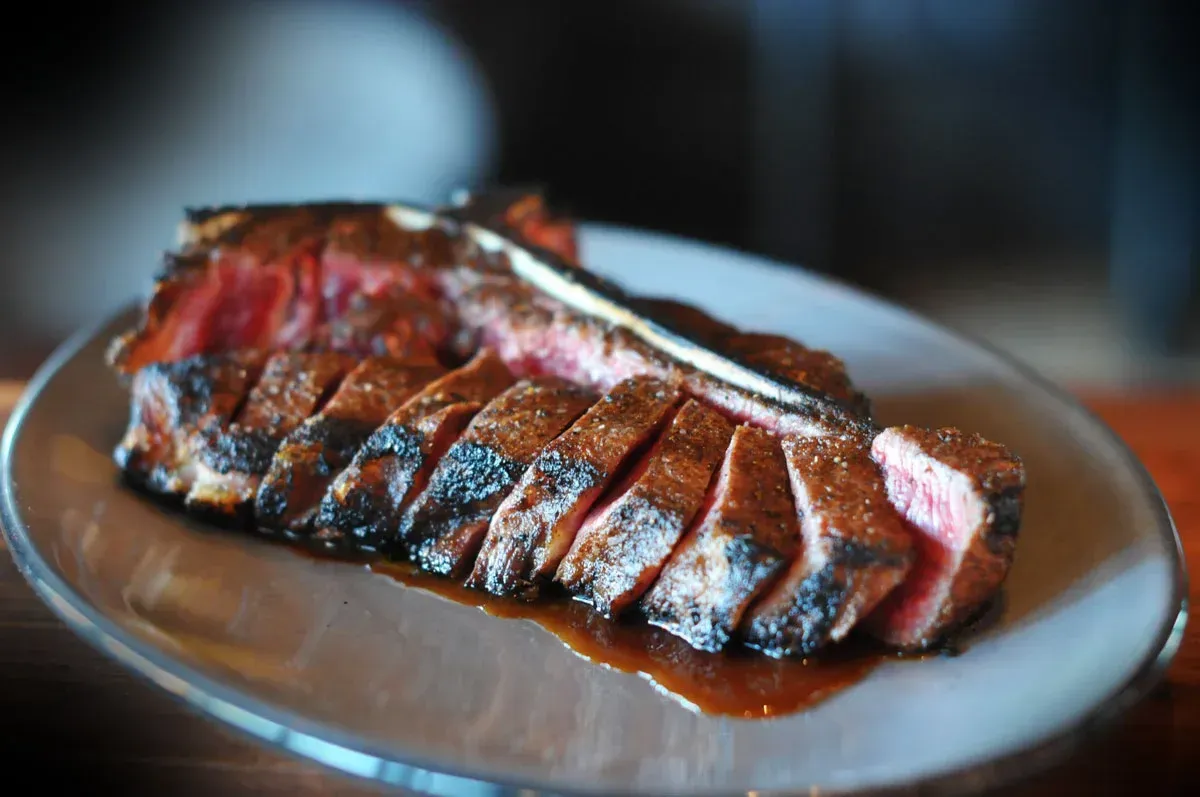Sliced grilled steak on a plate, with a charred crust and pink center