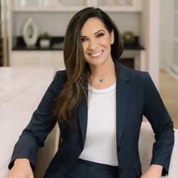 Smiling woman in navy blazer and white top standing in a bright modern room