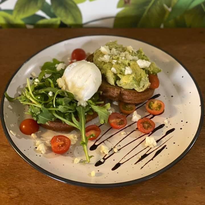 A Plate of Food With Avocado, Tomatoes and a Poached Egg on a Table — Memories Cafe @ Yorkeys Knob in Yorkeys Knob, QLD