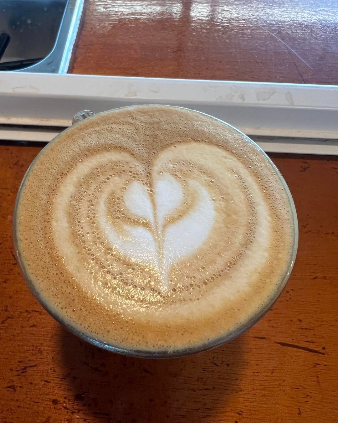 Latte With Heart-shaped Foam Art in a Clear Glass on a Wooden Table — Memories Cafe @ Yorkeys Knob in Yorkeys Knob, QLD