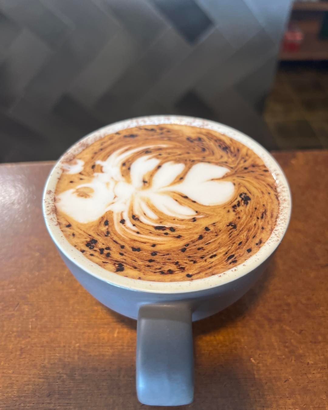 Latte With a Leaf Design in a Blue Mug on a Wooden Surface — Memories Cafe @ Yorkeys Knob in Yorkeys Knob, QLD