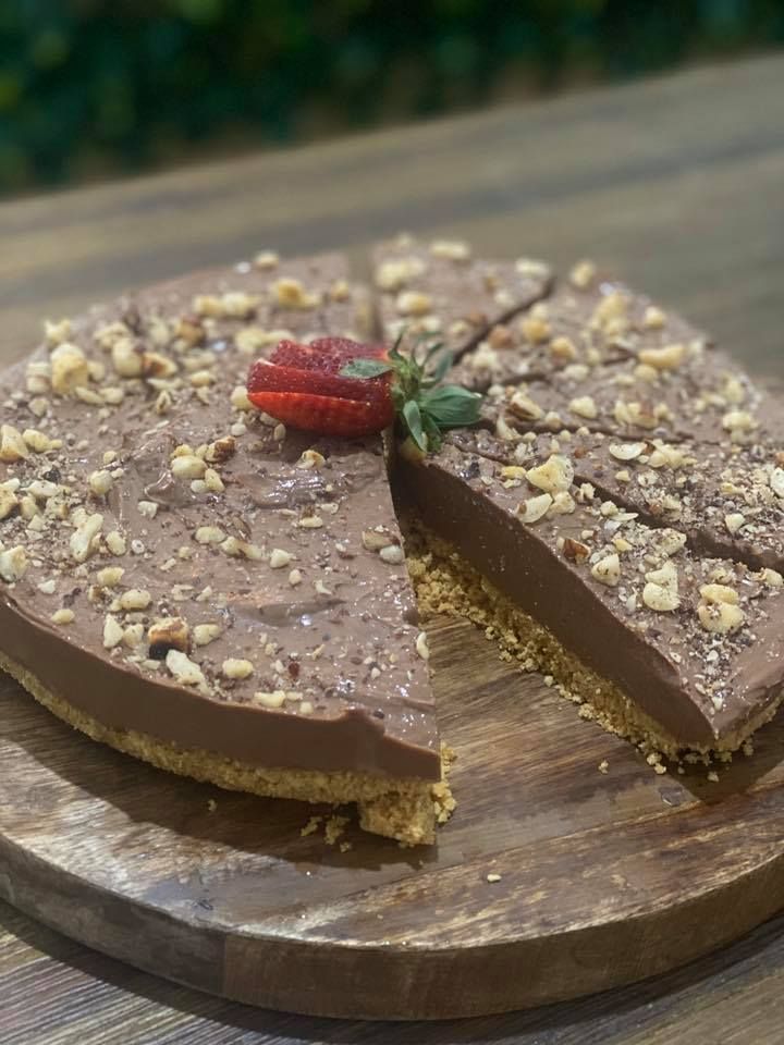 Chocolate Cheesecake With Nuts and a Strawberry on a Wooden Board — Memories Cafe @ Yorkeys Knob in Yorkeys Knob, QLD