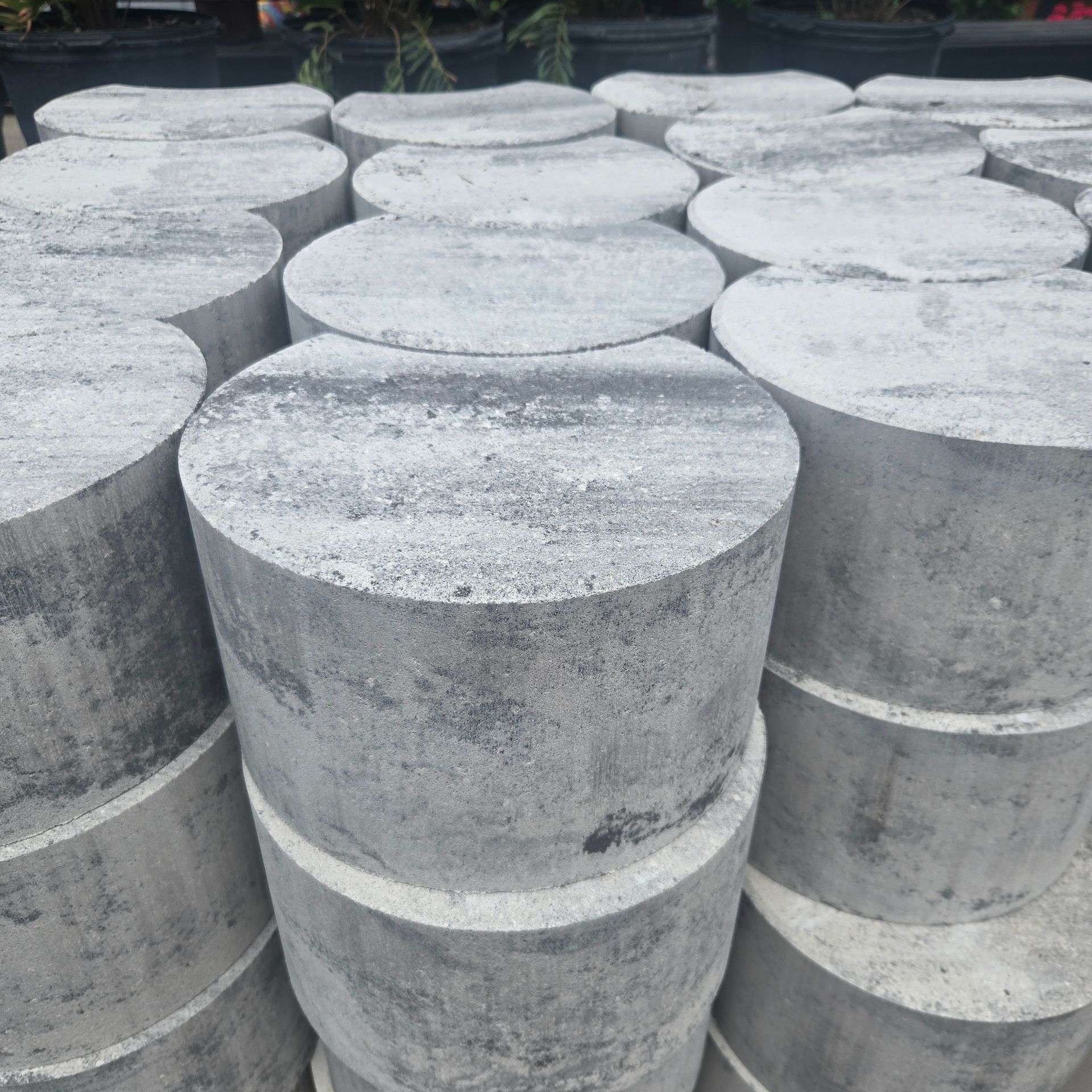 Stacks of large gray concrete cylinders arranged outdoors in rows