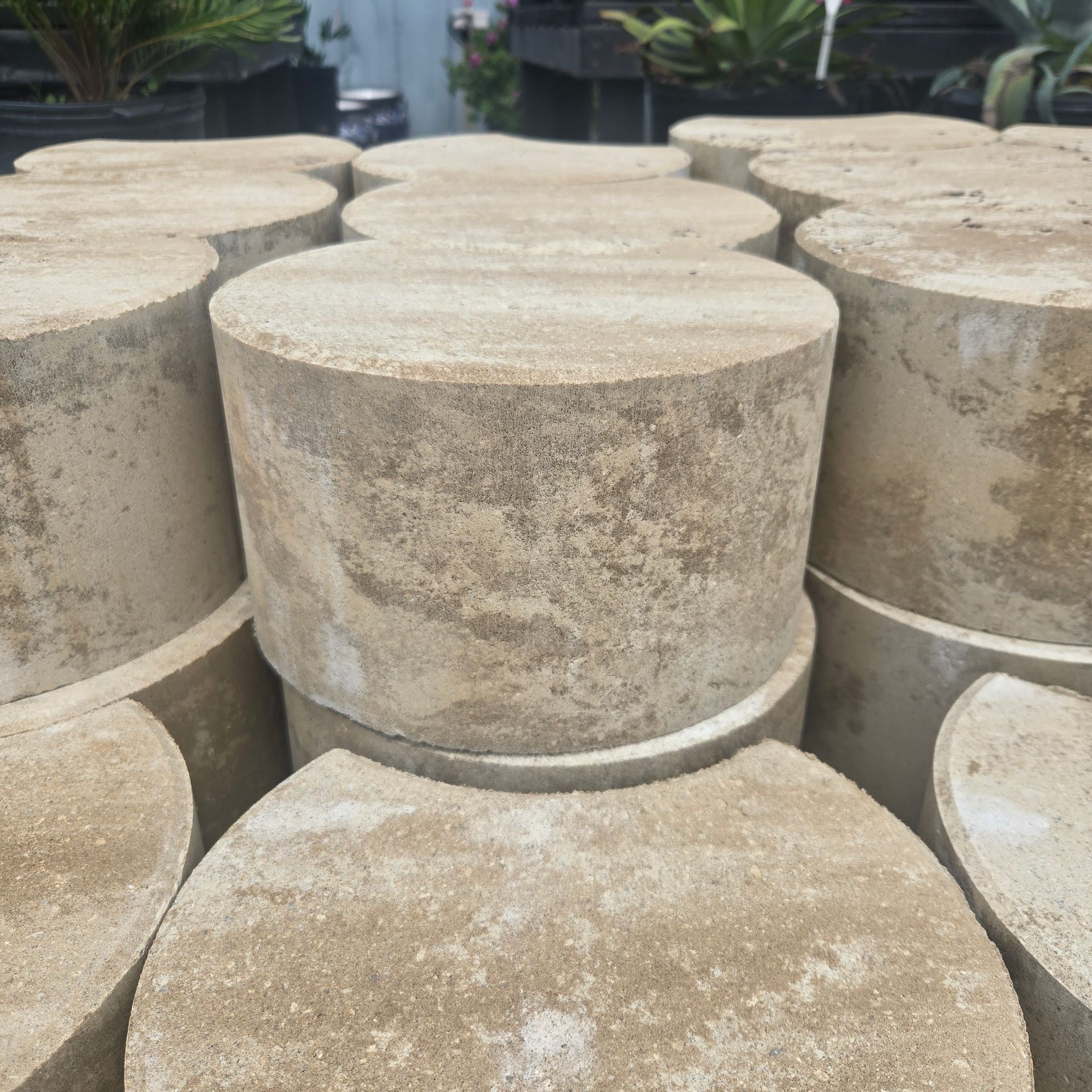 Stacked beige concrete cylinders outdoors in a yard or garden