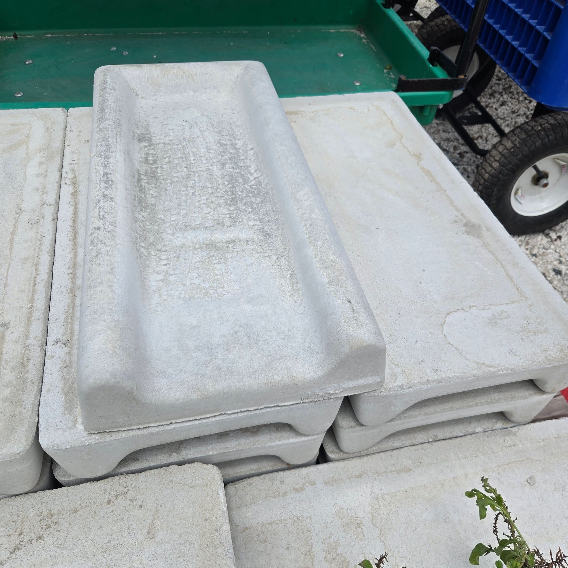 Stacked white foam packaging trays on a green cart outdoors.