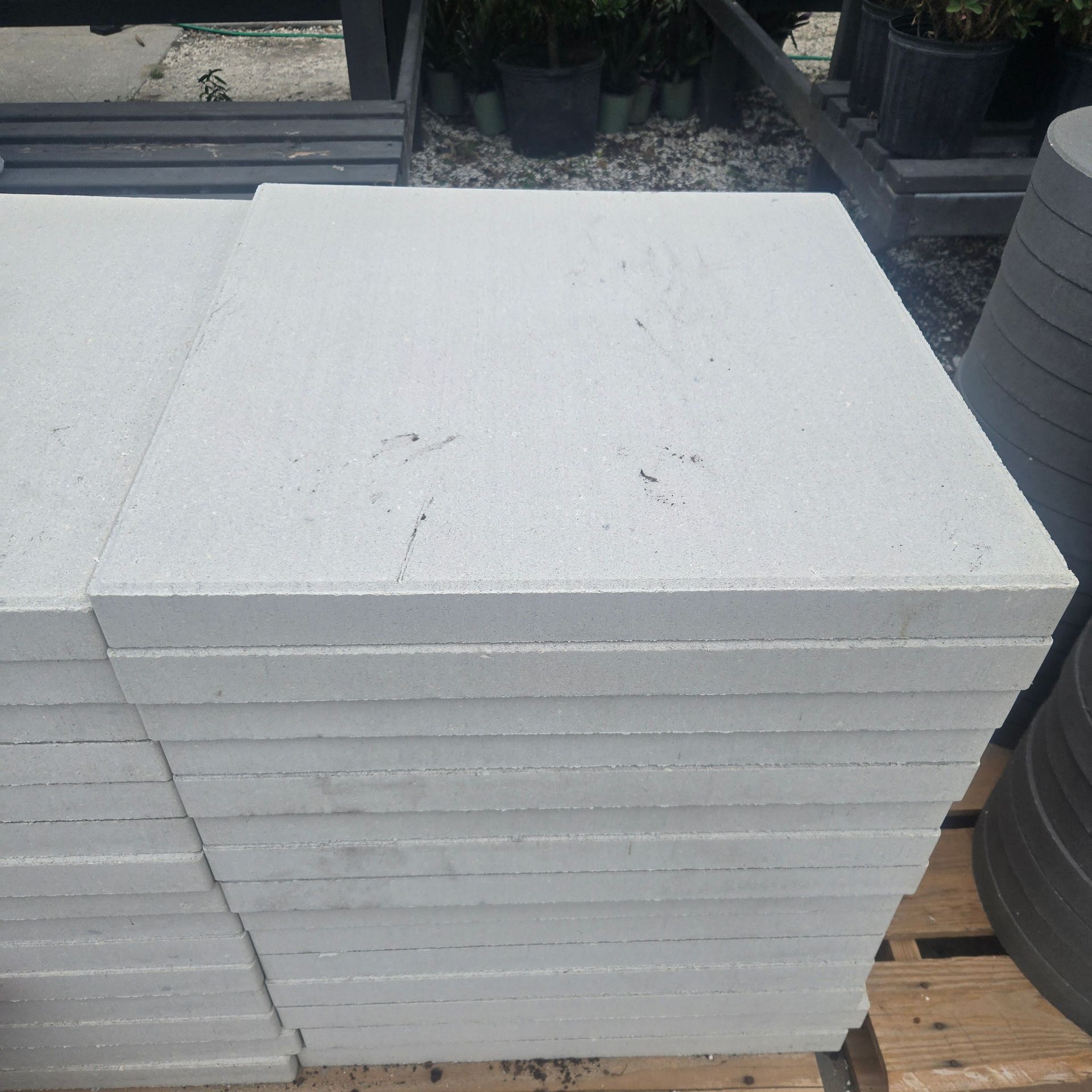 Stack of white foam boards or panels stacked outdoors on a wooden surface.