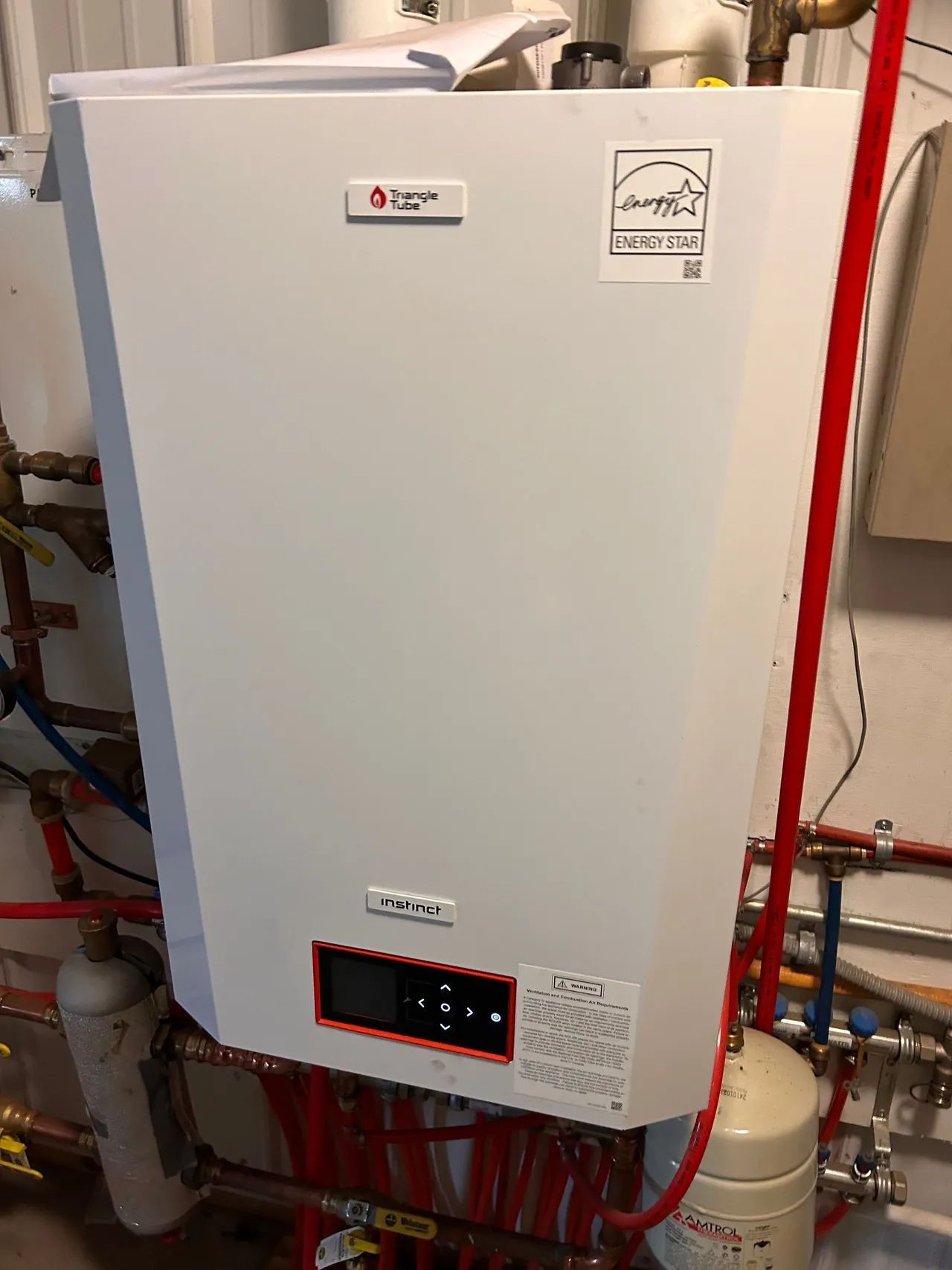 White wall-mounted boiler with red and copper piping; Energy Star label visible.