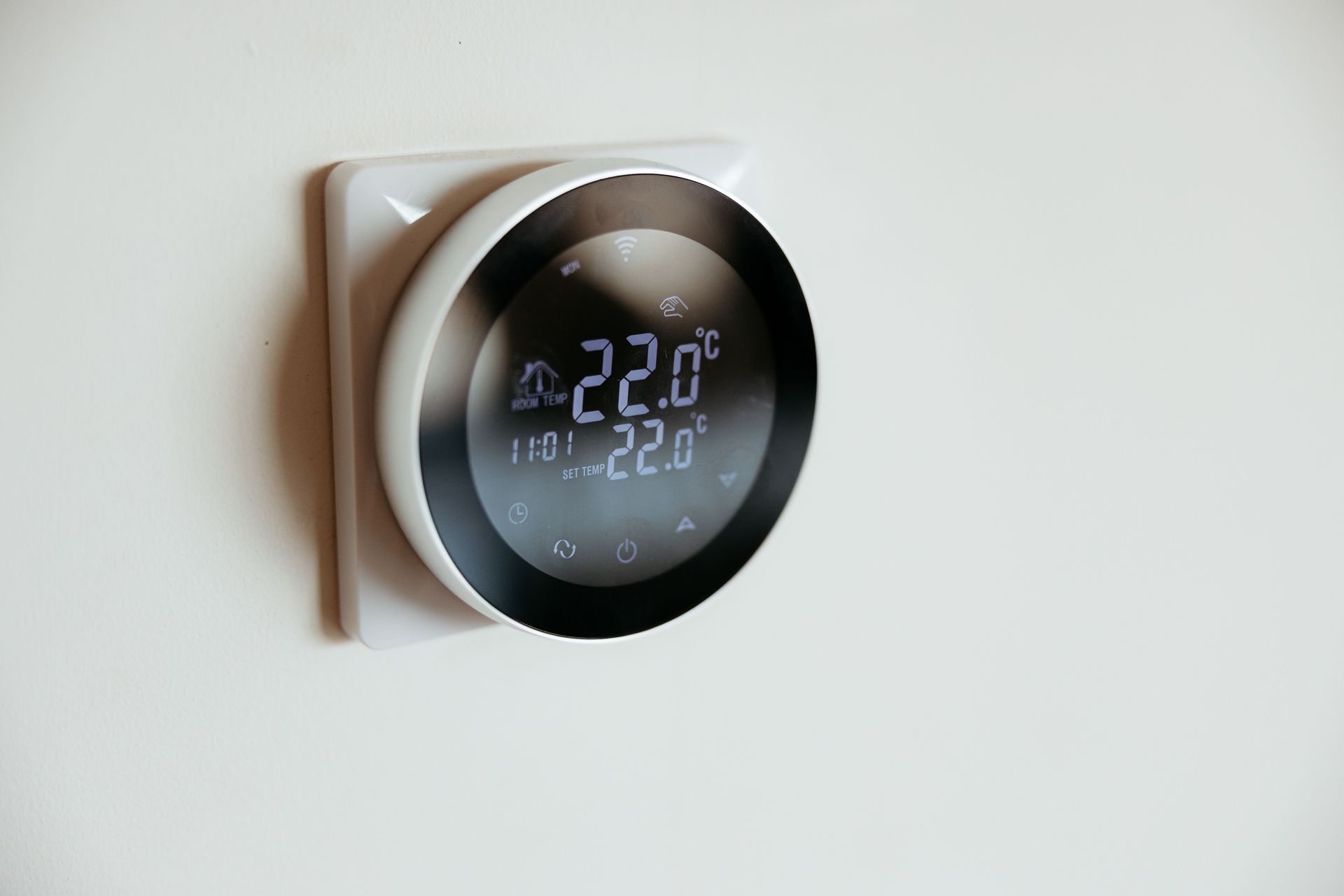 Smart thermostat showing a temperature of 22.0°C against a white wall.