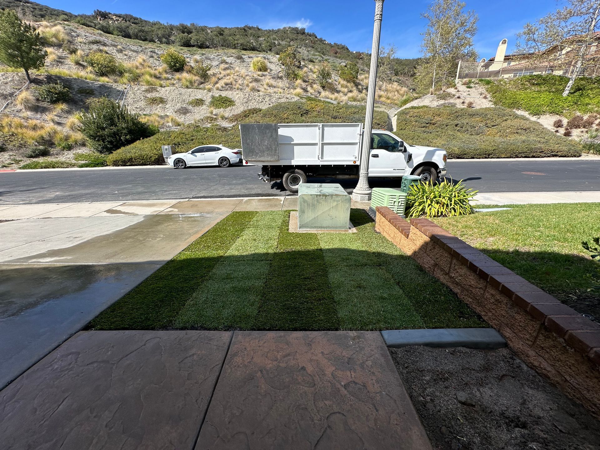 A white truck is parked in front of a lush green lawn.