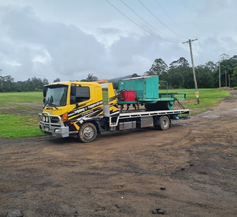 A Yellow Tow Truck is Parked on the Side of a Dirt Road — Wyong and Tuggerah Towing Service in Tuggerah, NSW