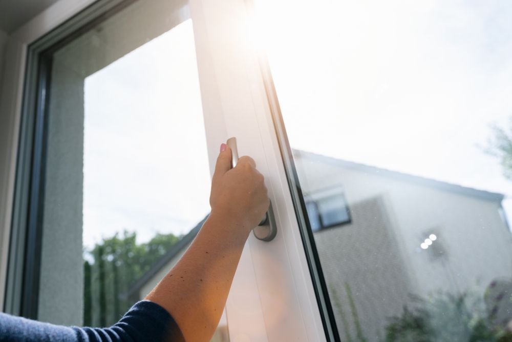 Hand Opening a White Window With Bright Sunlight Shining Through — Sams Glass Solutions in Proserpine, QLD