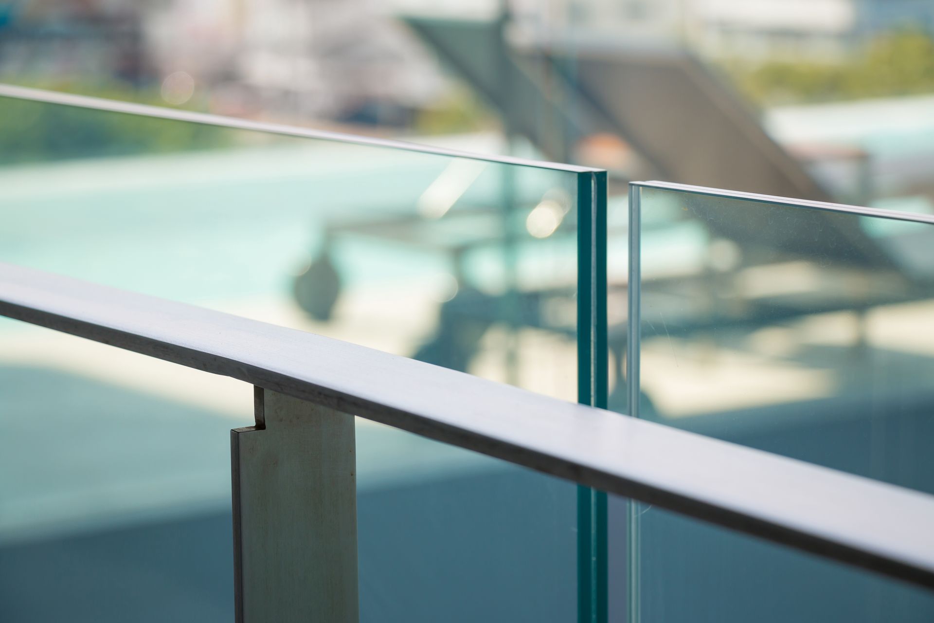 Metal Railing With Glass Panel on a Balcony Overlooking a Blurred Background — Sams Glass Solutions in Airlie Beach, QLD
