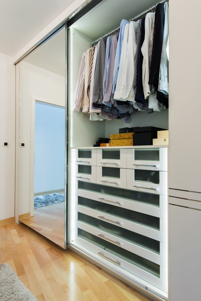 A Modern Open Closet With Hanging Shirts and Illuminated White Drawers — Sams Glass Solutions in Proserpine, QLD