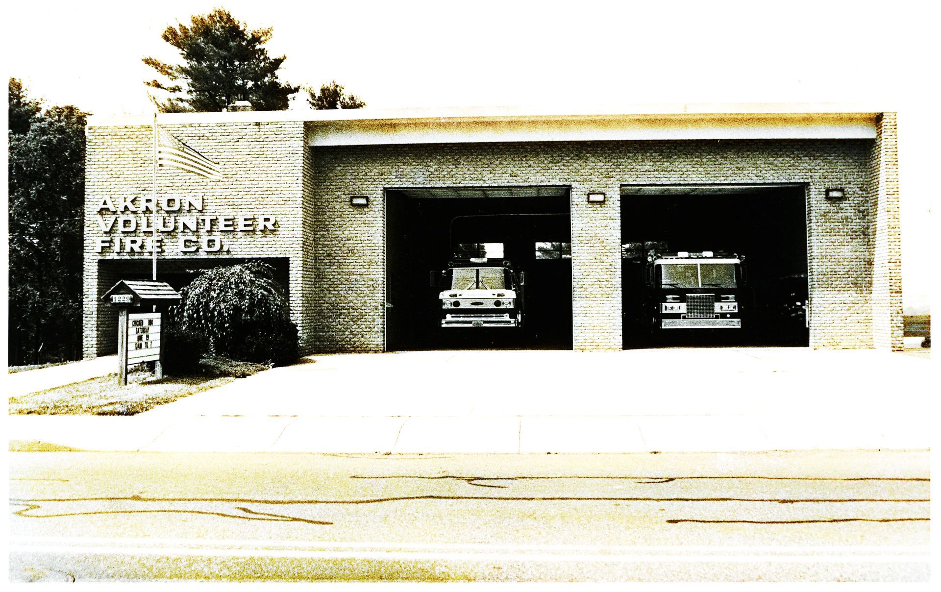 Older photo of fire engines parked in fire house.