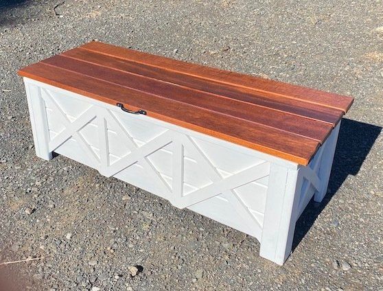 White storage bench with wood top on gravel outdoors