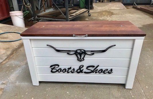 White wooden boots and shoes storage chest with brown top and black decorative lettering.