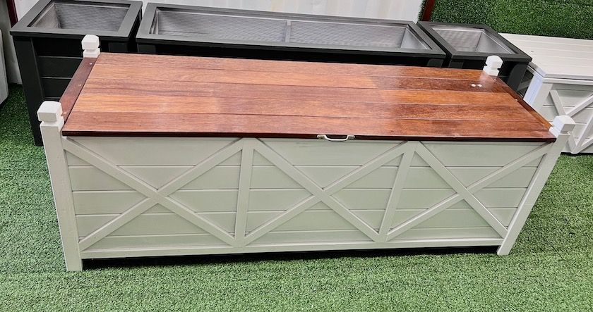 Outdoor planter bench with gray lattice sides, black tray top, and wood lid on grass