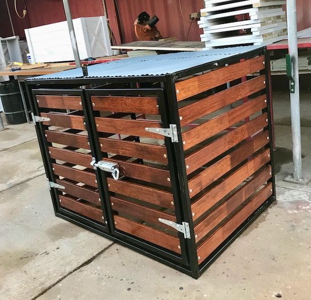 Black metal-and-wood storage bin with slatted sides in a workshop setting
