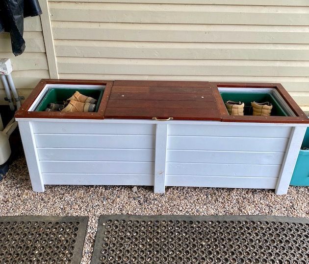 White wooden planter bench with a brown top and two open storage compartments on a porch