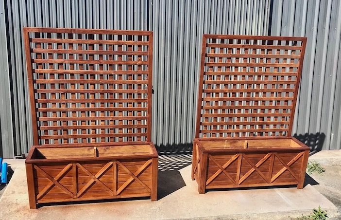 Two wooden lattice-back benches against a corrugated metal wall outdoors.