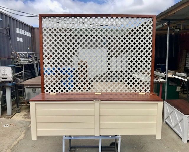 Outdoor cream display counter with a white lattice back panel and brown top on a wheeled stand