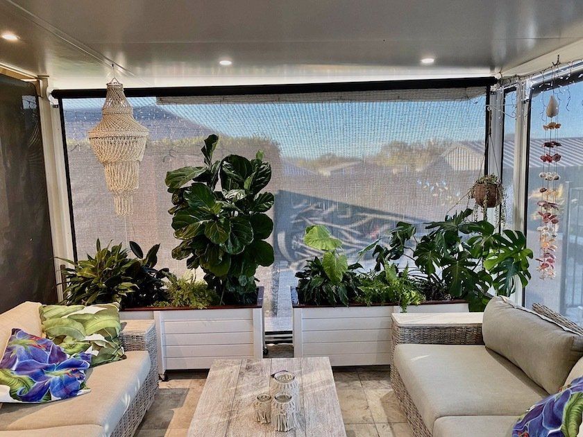 Bright living room with large windows, beige sofas, indoor plants, and a wooden coffee table with a mountain view.