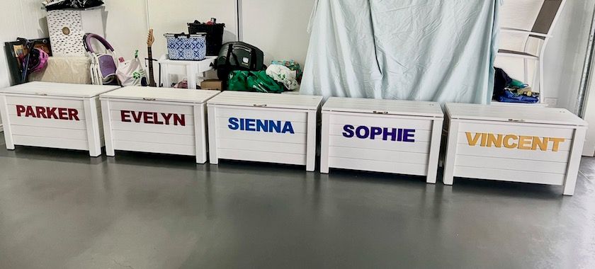 Five white bins labeled Parker, Evelyn, Sienna, Sophie, and Vincent in a row on a floor