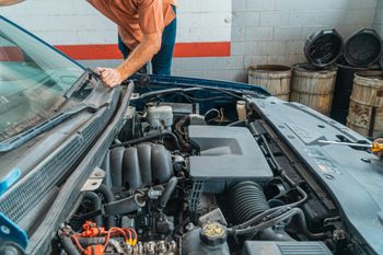 Technician Inspecting Engine Components Under Vehicle Hood | True North Automotive