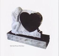 A black heart-shaped headstone on a rock-cut base with a carved figure leaning against it in a pose of mourning.