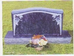 A dark polished granite headstone with decorative floral corner carvings, sitting on a base in a grassy cemetery.