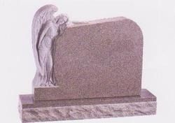 A granite tombstone with an angel carved on the left side, resting its hand on the headstone.