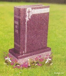 A dark purple granite headstone shaped like an open book, engraved with a cross, sitting on a grassy lawn.