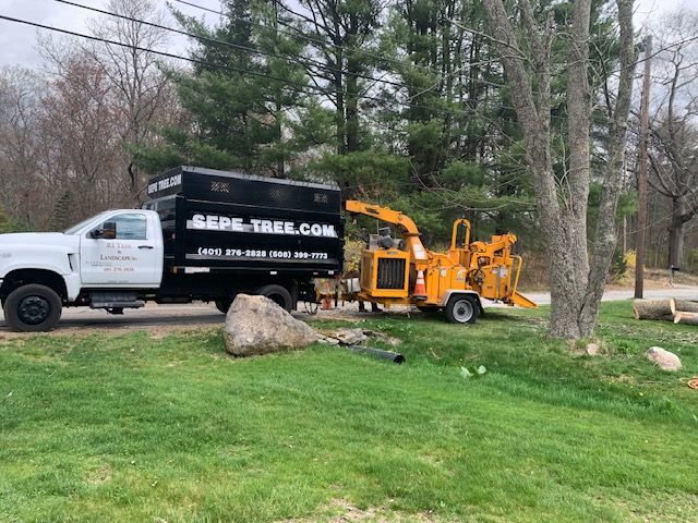 A truck is parked next to a tree chipper in a yard.